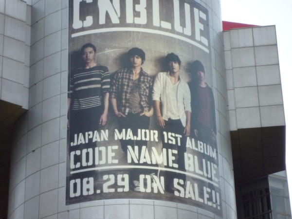 ファッションビル「渋谷109」にCNBLUEが明日29日のリリースを控えたメジャー1stアルバム「CODE NAME BLUE」の巨大ビジュアルボードが掲示されている。（2012年8月24日、東京都渋谷区）